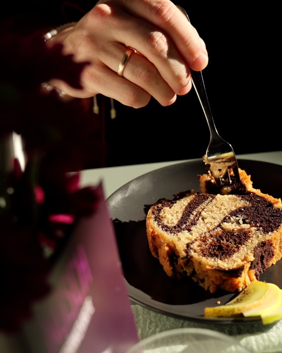 Eine Hand sticht mit der Kuchengabel in ein Stück Marmorkuchen